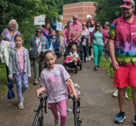 Reilly in her walker walking in front of the rest of the community in a marathon
