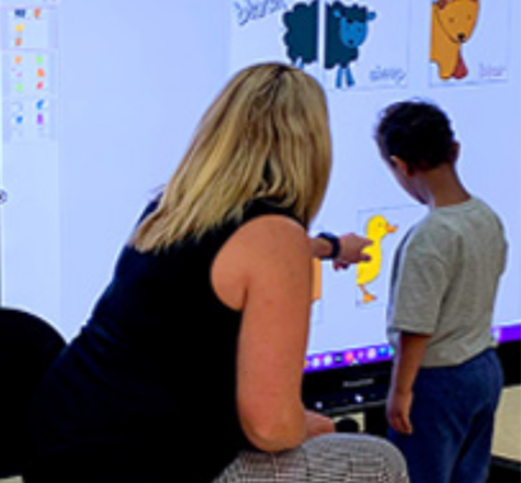 Adult and child sitting infront of TV whiteboard working on sensory activity